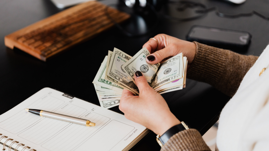 person counting money over an accounting book